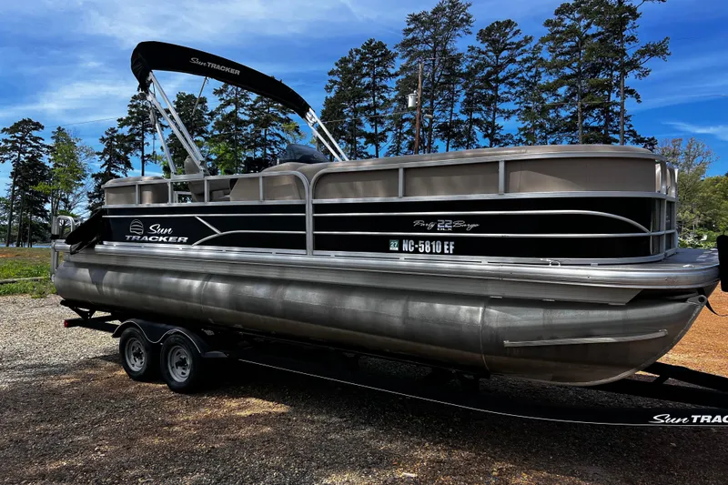 The Image of 2017 Sun Tracker Party Barge 22 DLX pontoon boat on trailer, surrounded by trees. - 0