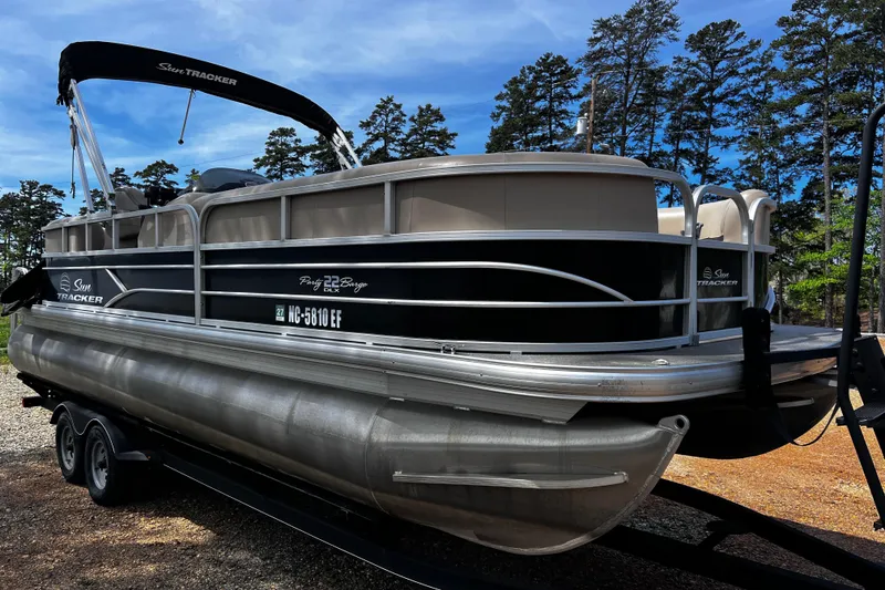 Slide: The Image of 2017 Sun Tracker Party Barge 22 DLX pontoon boat on trailer, surrounded by trees. - 3