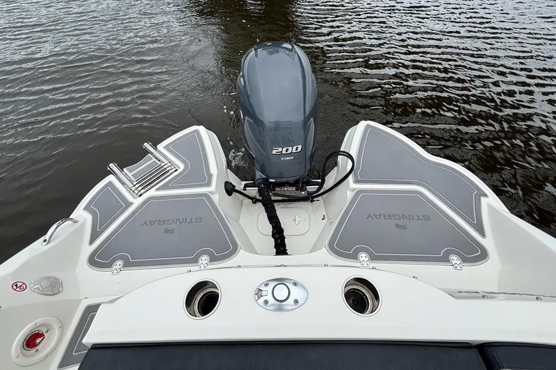 Slide: The Image of 2021 Stingray 231 DC boat on calm water with lush green background. - 15