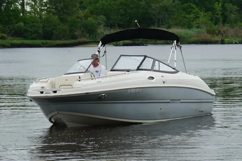 Slide: The Image of 2021 Stingray 231 DC boat cruising on a calm river with lush green trees. - 17