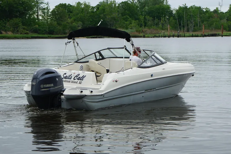 Slide: The Image of 2021 Stingray 231 DC boat on calm water with lush green background. - 21