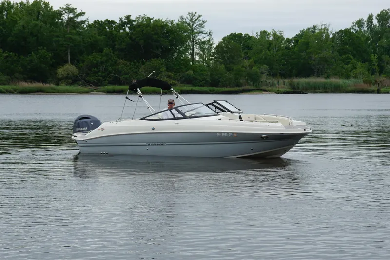 Slide: The Image of 2021 Stingray 231 DC boat on calm water with lush green background. - 22