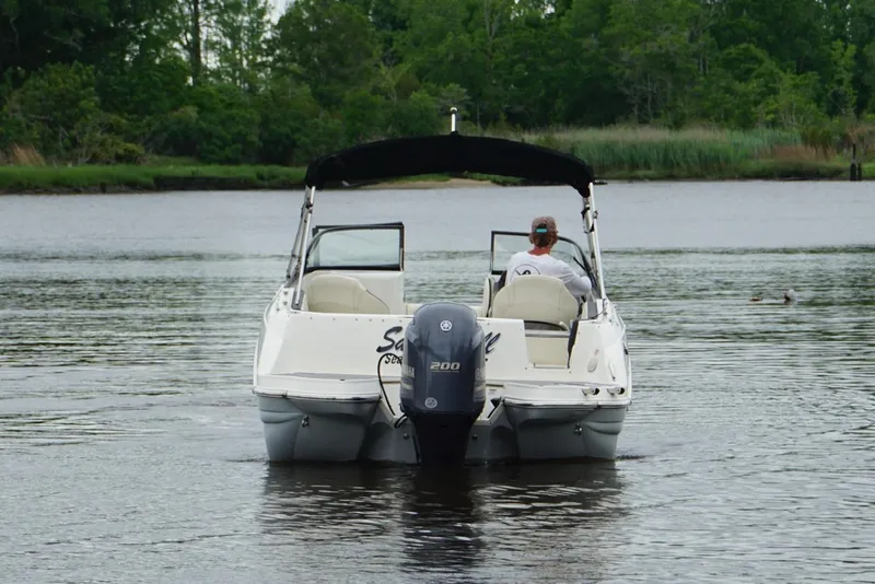 Slide: The Image of 2021 Stingray 231 DC boat cruising on a calm river with lush greenery. - 3