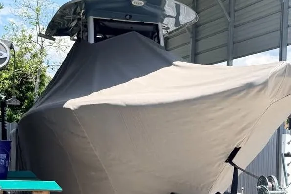Slide: The Image of 2023 Sea Hunt Ultra 239 SE boat covered in protective tarp under a shelter. - 11
