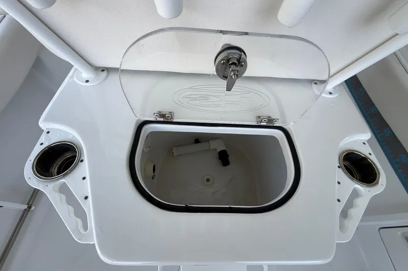 Slide: The Image of 2023 Sea Hunt Ultra 239 SE boat storage compartment with open lid and cup holders. - 7
