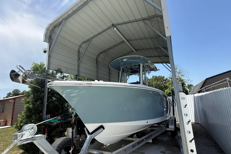 Slide: The Image of 2023 Sea Hunt Ultra 239 SE boat under a metal canopy, on a trailer. - 22