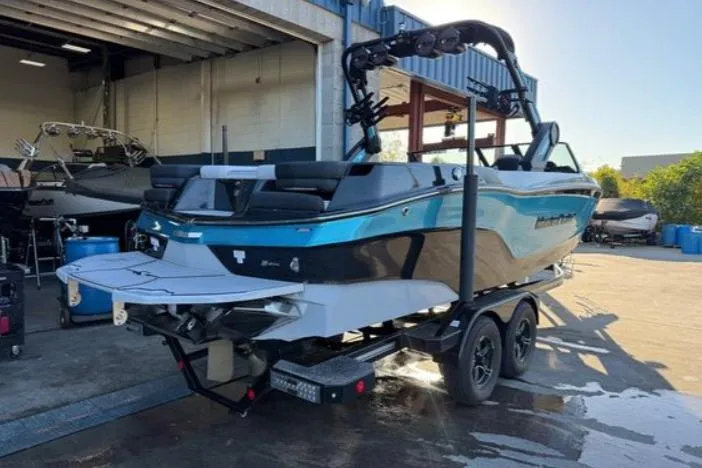 Slide: The Image of 2023 MasterCraft XT24 boat on trailer in a marina setting. - 2