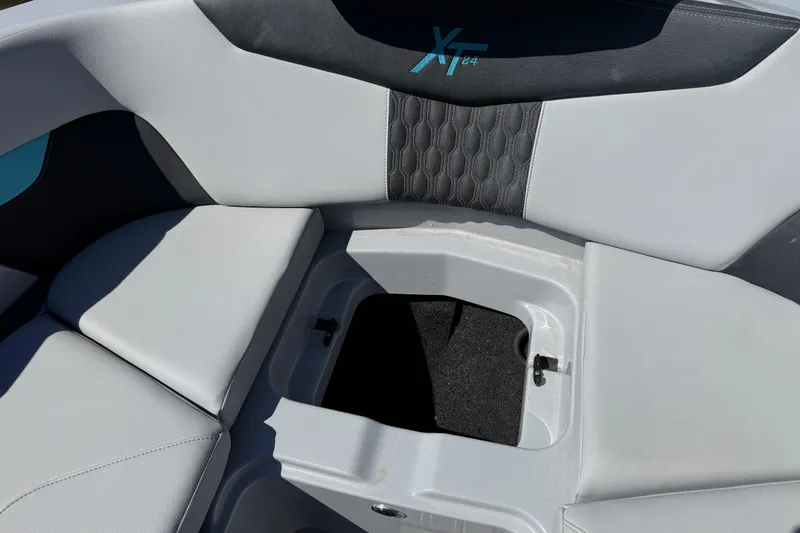 Slide: The Image of 2023 MasterCraft XT24 boat interior with open storage compartment and cushioned seating. - 4