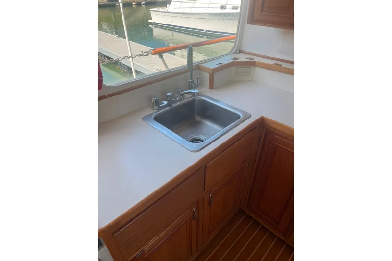 Slide: The Image of 1972 DeFever 38 Passagemaker kitchen sink with wooden cabinetry and marina view. - 12