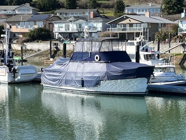 Slide: The Image of 1972 DeFever 38 Passagemaker yacht docked, covered in blue tarp, with waterfront homes in background. - 3