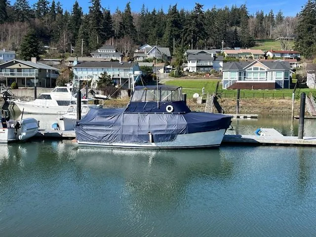 Slide: The Image of 1972 DeFever 38 Passagemaker docked, covered in blue tarp, with waterfront homes in the background. - 4