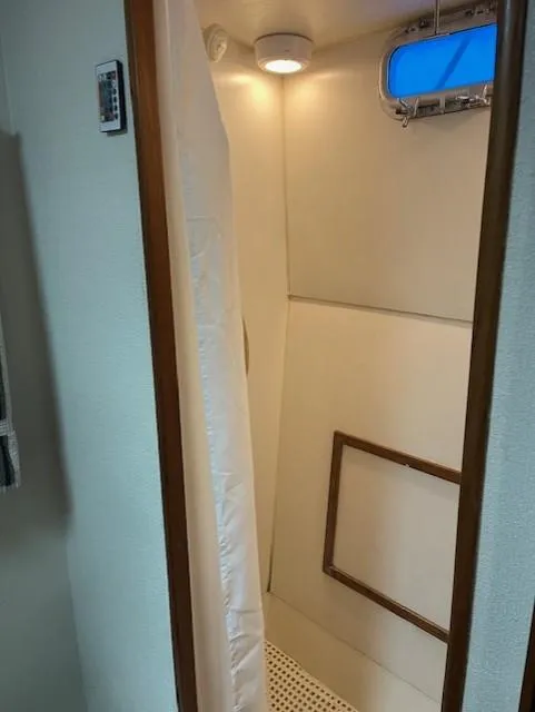 Slide: The Image of Shower area inside 1972 DeFever 38 Passagemaker boat, featuring a curtain and small window. - 64