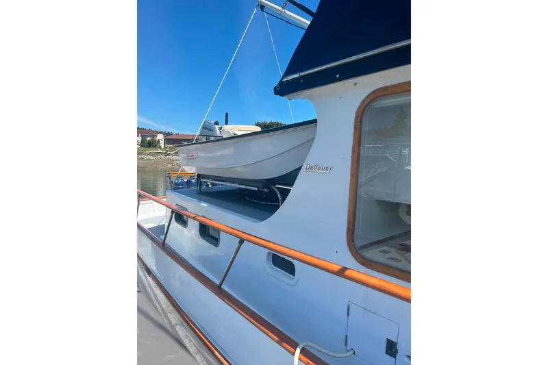 Slide: The Image of 1972 DeFever 38 Passagemaker yacht with dinghy on deck, docked under clear blue sky. - 88