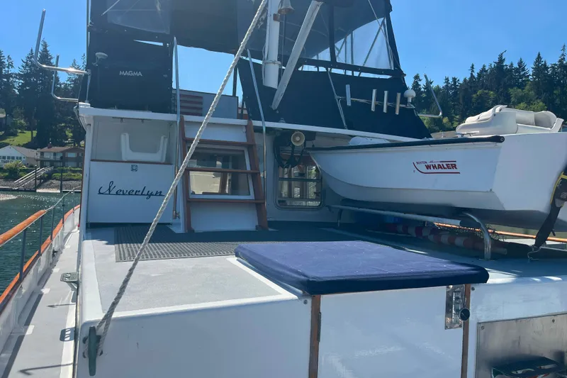 Slide: The Image of 1972 DeFever 38 Passagemaker yacht deck with Boston Whaler boat, docked near scenic shoreline. - 90
