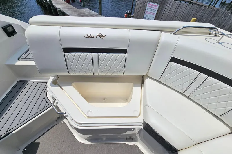 Slide: The Image of 2018 Sea Ray SLX 230 boat interior with white cushioned seating and storage compartment. - 23
