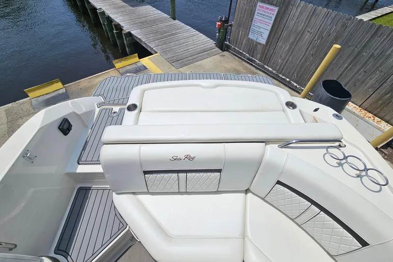 Slide: The Image of 2018 Sea Ray SLX 230 boat interior with white seating and dockside view. - 24