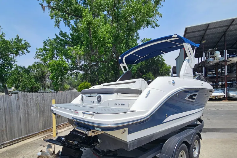 Slide: The Image of 2018 Sea Ray SLX 230 boat on trailer, featuring sleek design and blue canopy. - 3