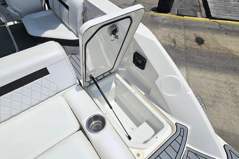 Slide: The Image of 2018 Sea Ray SLX 230 boat interior with open storage compartment and cup holder. - 31