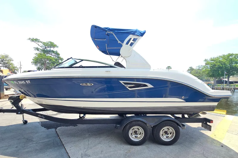 Slide: The Image of 2018 Sea Ray SLX 230 boat on trailer, blue and white design, parked near water. - 5