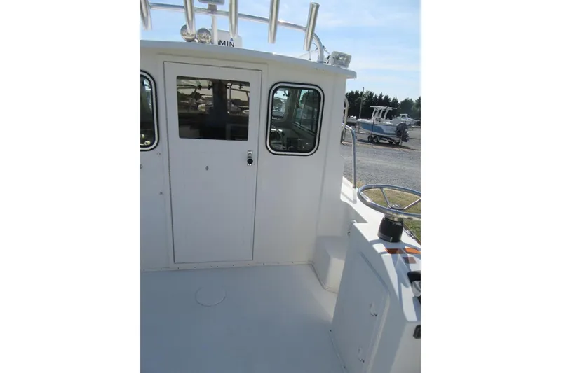 Slide: The Image of 2013 Parker 2320 SL Sport Cabin boat deck with steering wheel and cabin door. - 17