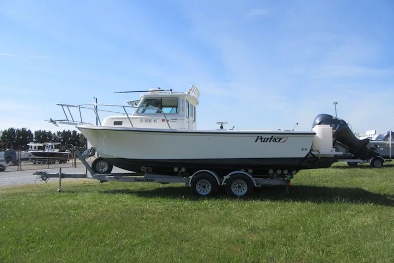 Slide: The Image of 2013 Parker 2320 SL Sport Cabin boat on trailer, parked on grass under clear sky. - 2