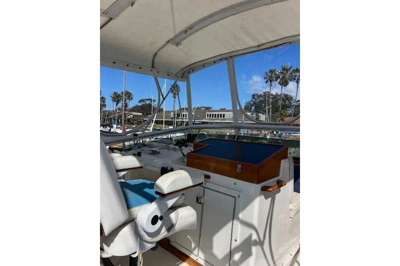Slide: The Image of 1985 Egg Harbor 33 Convertible boat interior with helm, white seating, and marina view. - 10