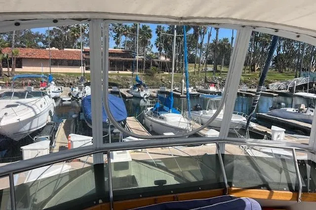 Slide: The Image of 1985 Egg Harbor 33 Convertible yacht docked at a marina with sailboats and palm trees. - 13