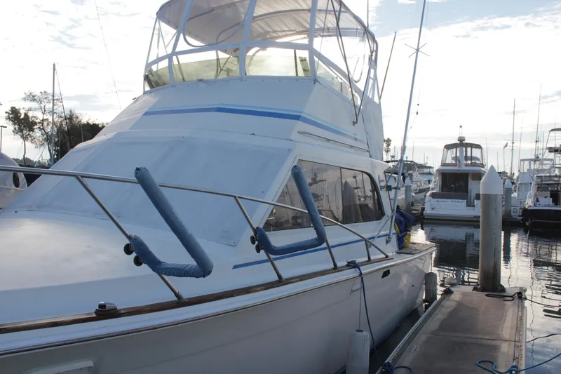 Slide: The Image of 1985 Egg Harbor 33 Convertible yacht docked at marina, showcasing sleek design and spacious deck. - 2