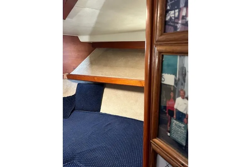 Slide: The Image of 1985 Egg Harbor 33 Convertible cabin interior with blue bedding and framed photos. - 27