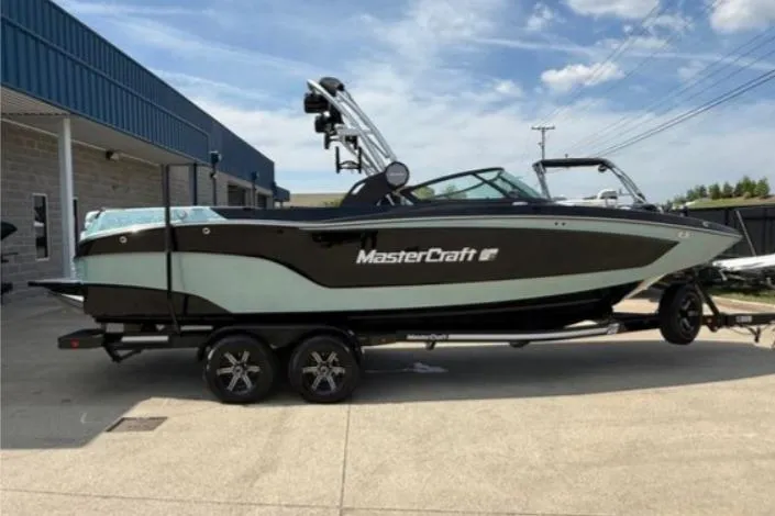 The Image of 2022 MasterCraft XT24 boat on trailer, parked outdoors near a building. - 0
