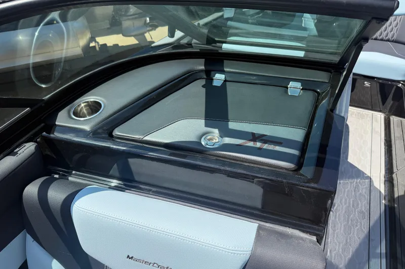 Slide: The Image of 2022 MasterCraft XT24 boat interior with storage compartment and cup holder. - 18