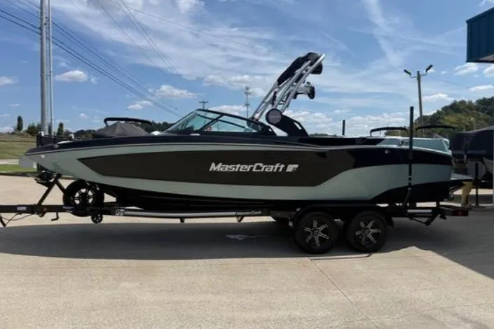 Slide: The Image of 2022 MasterCraft XT24 boat on trailer, parked outdoors under a clear blue sky. - 2