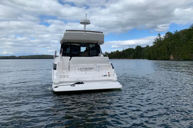Slide: The Image of 2019 Regal 42 Grande Coupe yacht on a serene lake under a cloudy sky. - 3