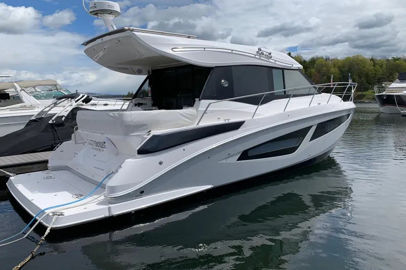 Slide: The Image of 2019 Regal 42 Grande Coupe yacht docked on a calm lake under cloudy skies. - 37