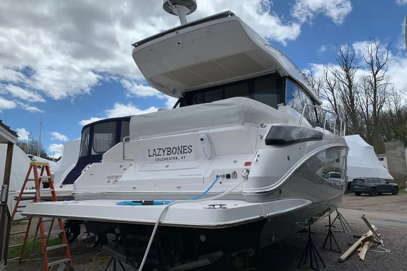 Slide: The Image of 2019 Regal 42 Grande Coupe yacht on land, named "Lazybones," under a cloudy sky. - 43