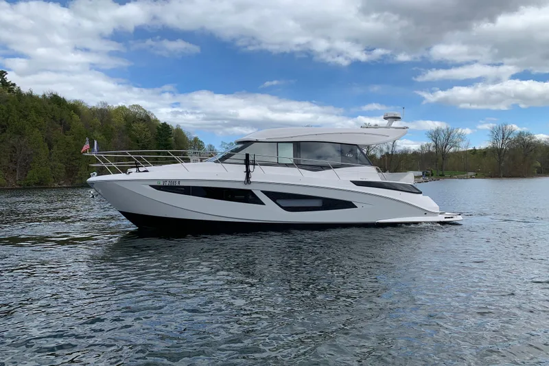 Slide: The Image of 2019 Regal 42 Grande Coupe yacht cruising on a serene lake under a partly cloudy sky. - 5