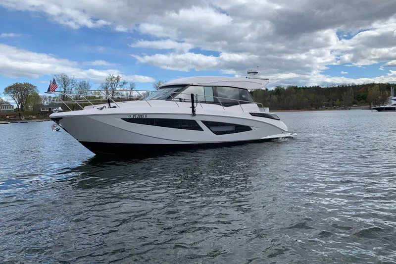Slide: The Image of 2019 Regal 42 Grande Coupe yacht on a serene lake under a cloudy sky. - 6