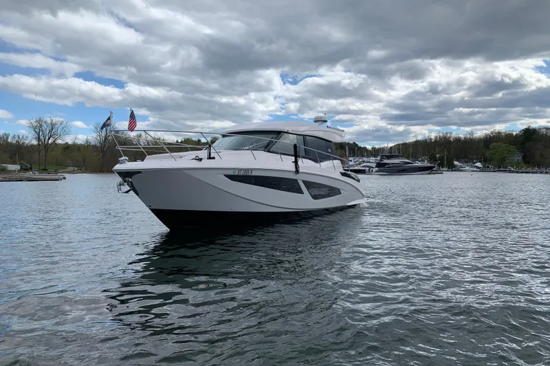 Slide: The Image of 2019 Regal 42 Grande Coupe yacht on a serene lake under cloudy skies. - 7