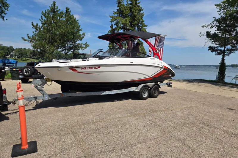 The Image of 2018 Yamaha Boats 242X on trailer by lakeside, ready for water adventure. - 0