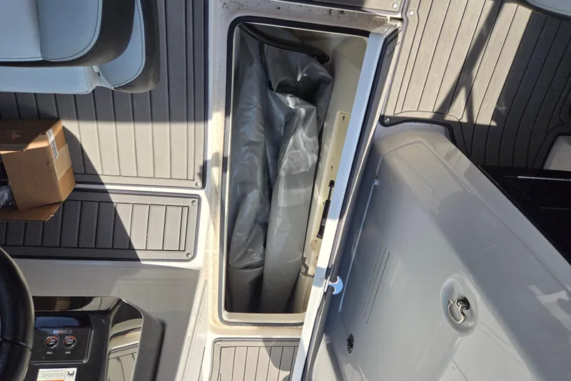 Slide: The Image of 2018 Yamaha Boats 242X storage compartment with gray flooring and a cardboard box. - 5