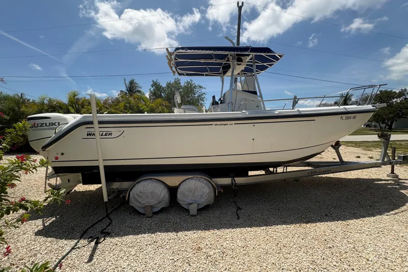 The Image of 1999 Boston Whaler 260 Outrage boat on trailer, sunny day, palm trees in background. - 1