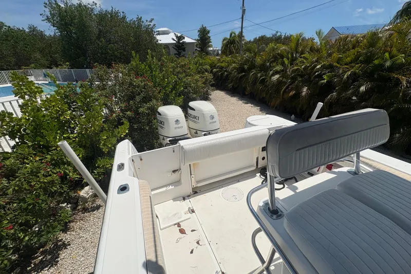 Slide: The Image of 1999 Boston Whaler 260 Outrage boat with dual Suzuki engines, surrounded by lush greenery. - 13