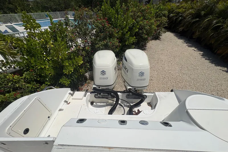 Slide: The Image of 1999 Boston Whaler 260 Outrage with twin Suzuki 250 engines, surrounded by lush greenery. - 14