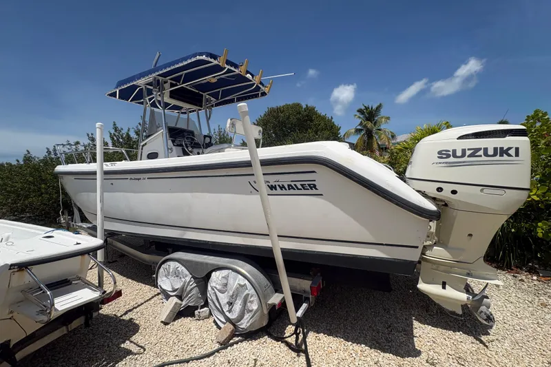Slide: The Image of 1999 Boston Whaler 260 Outrage boat with Suzuki engine on a trailer, parked outdoors. - 3