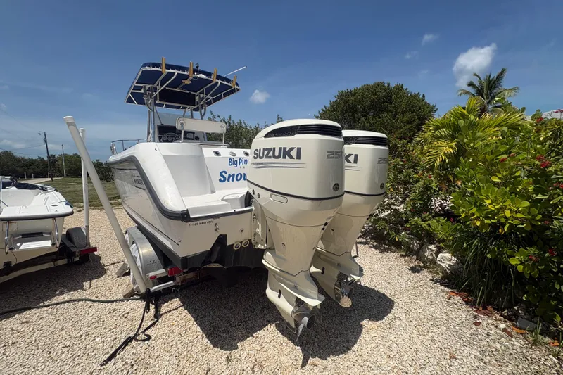 Slide: The Image of 1999 Boston Whaler 260 Outrage with twin Suzuki engines, parked on gravel. - 4