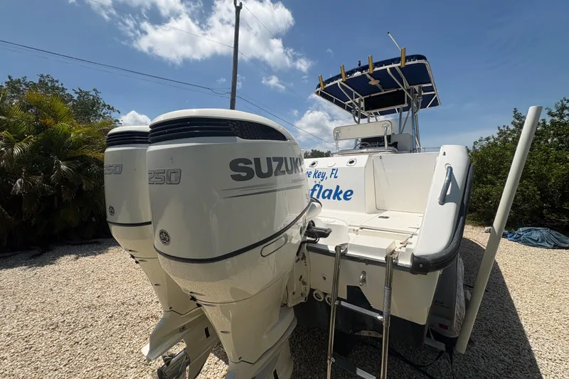 Slide: The Image of 1999 Boston Whaler 260 Outrage with twin Suzuki 250 engines, parked on gravel. - 5
