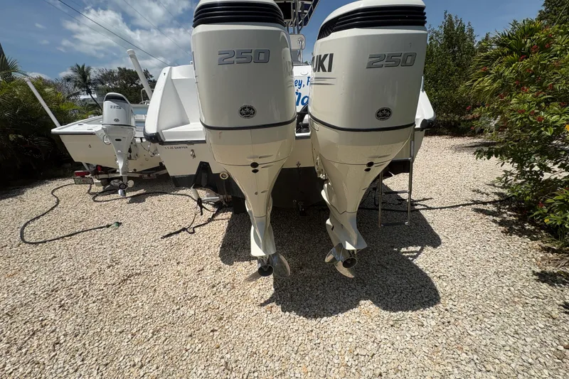 Slide: The Image of 1999 Boston Whaler 260 Outrage with dual Suzuki 250 outboard motors on gravel. - 6