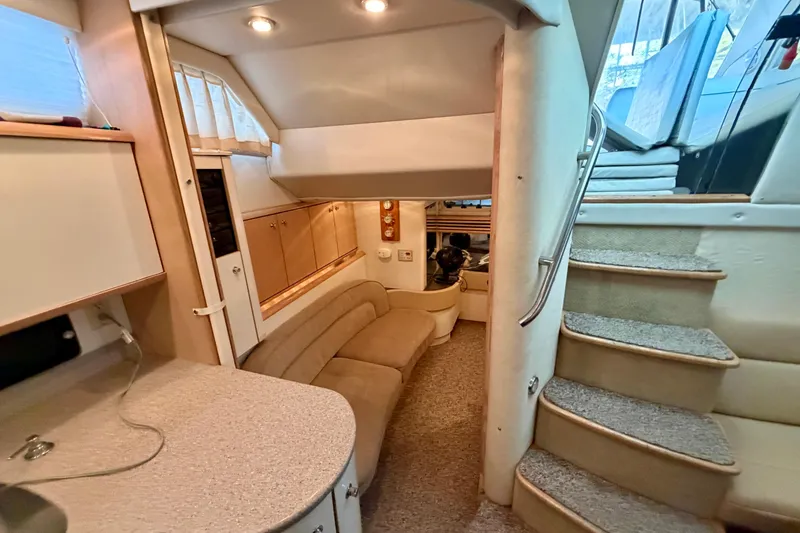 Slide: The Image of Interior of a 1997 Avanti 4085 Sunbridge yacht, featuring cozy seating and carpeted stairs. - 21