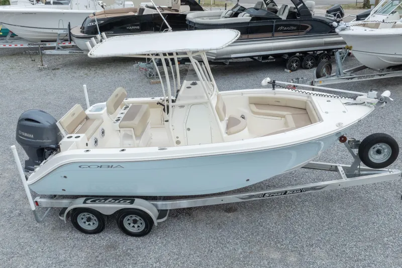 Slide: The Image of 2016 Cobia 201 Center Console boat on trailer, featuring Yamaha engine, parked on gravel. - 10