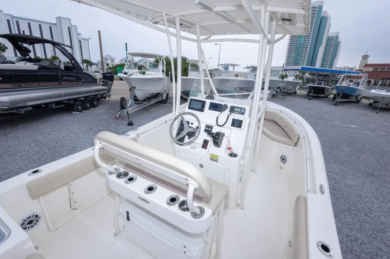 Slide: The Image of 2016 Cobia 201 Center Console boat interior with steering wheel and controls, parked in marina. - 19